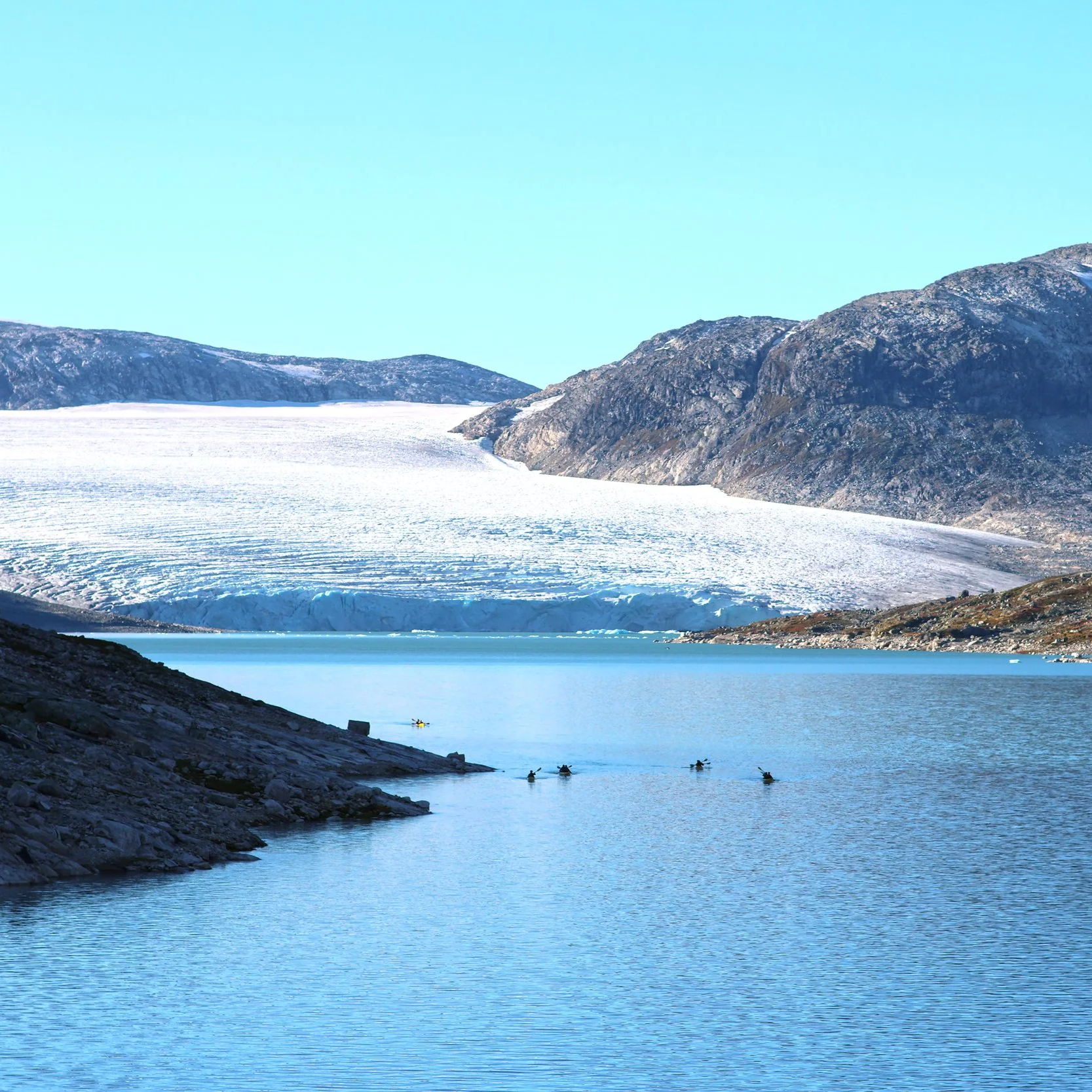 Kayaks navegando por Styggevatnet hacia un glaciar en desprendimiento en el Parque Nacional Jostedalsbreen, Noruega.
