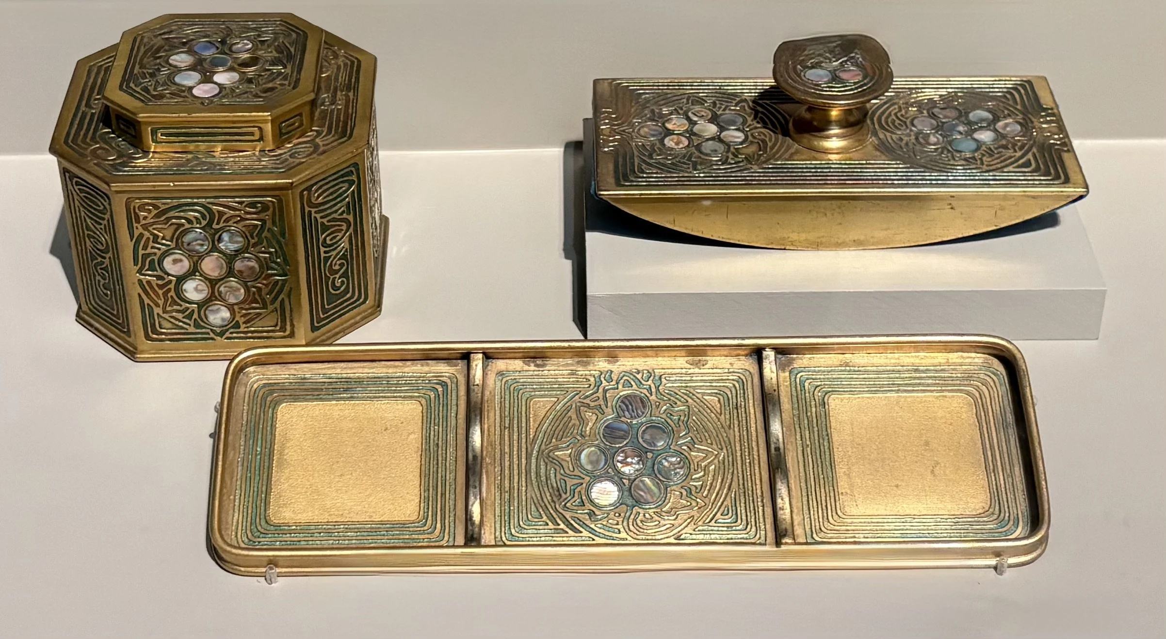 Tiffany Studios Abalone desk set. Decorative gold inlaid gaming or collectible items with intricate engraved patterns and circular stone or mirror accents arranged in a floral or geometric design.