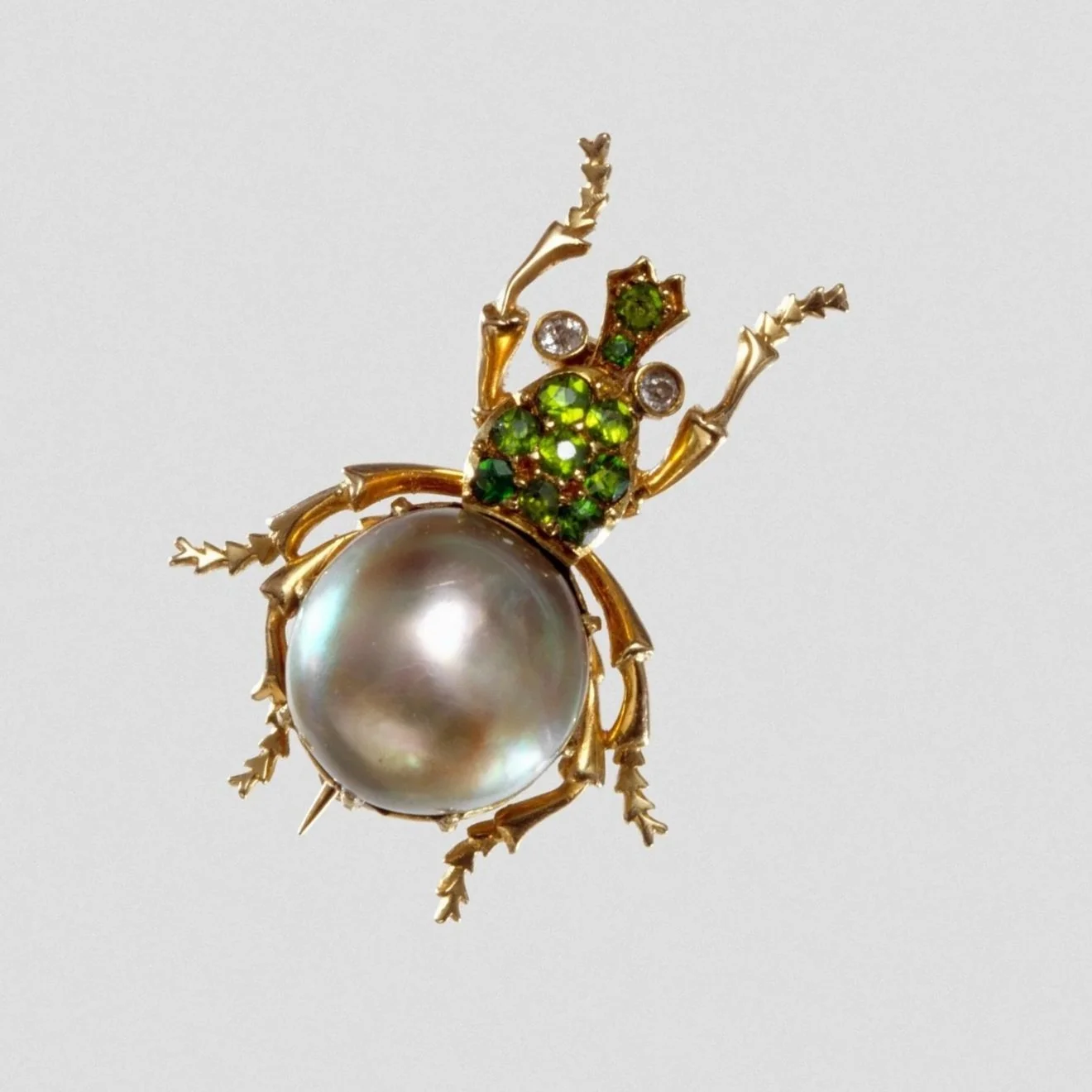 A decorative brooch in the shape of a beetle with a large pearl body.
