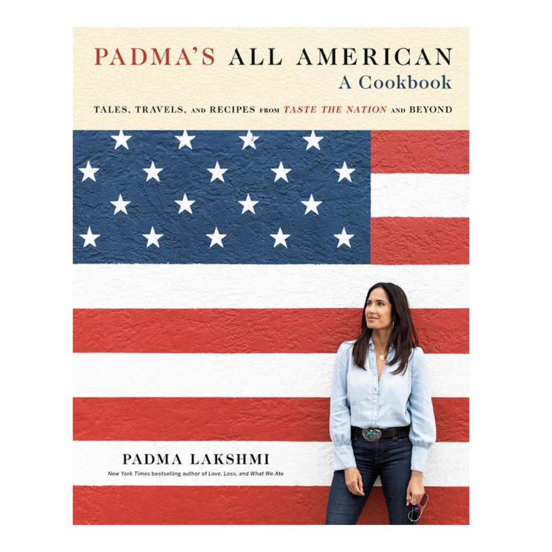 Book cover titled "Padma's All American: A Cookbook" with a woman standing in front of a textured American flag wall.