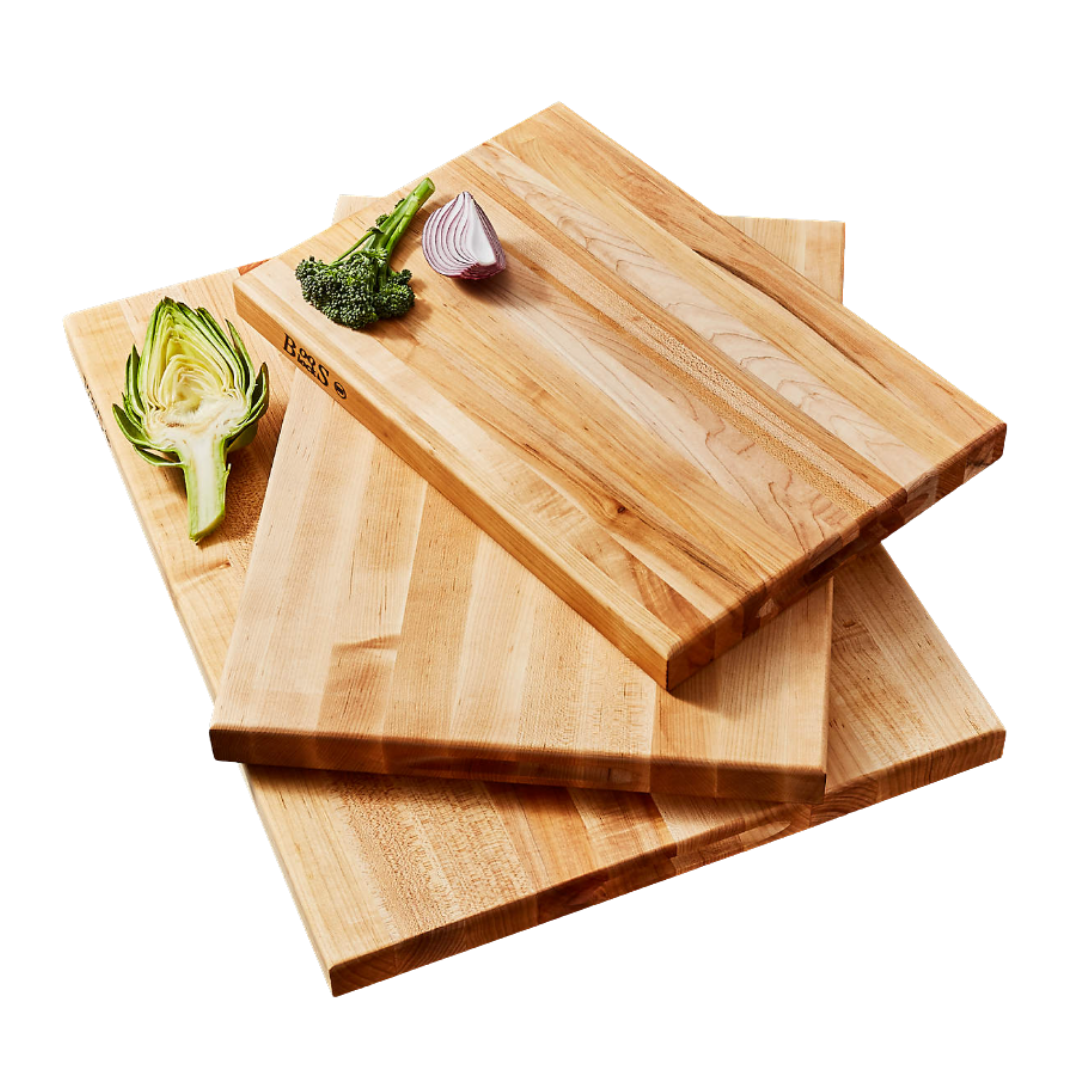 Three wooden cutting boards stacked, with vegetable pieces including broccoli, red onion, and artichoke on top.