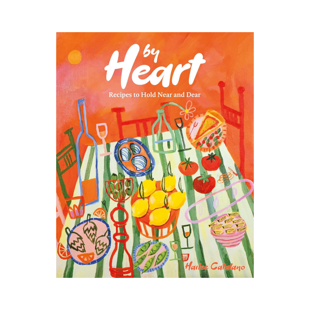 Colorful illustrated book cover titled "by Heart" with a subtitle "Recipes to Hold Near and Dear." The cover features a vibrant table setting with various food items, bottles, glasses, and a bowl of pasta, against an orange background.