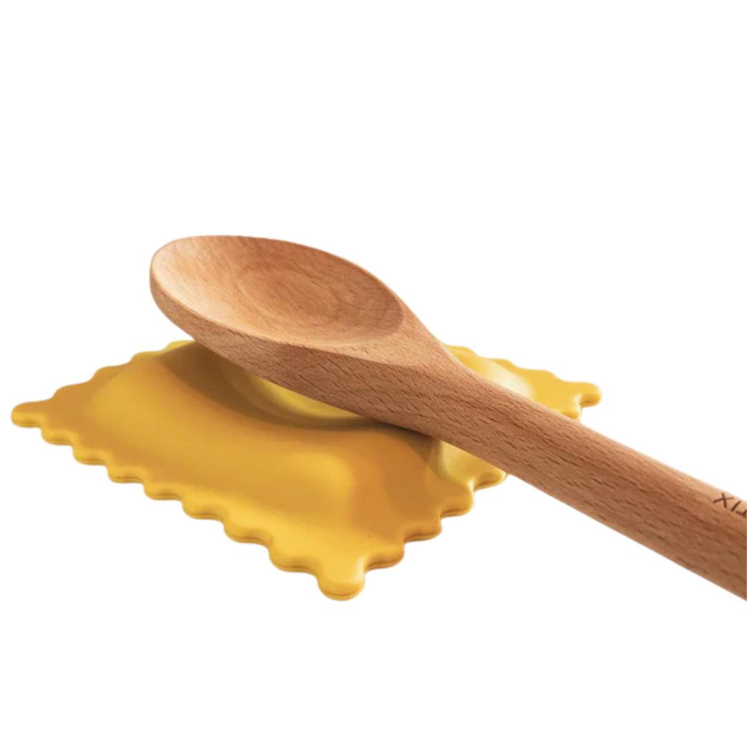 A yellow piece of ravioli pasta with a wooden spoon resting on top, set against a white background.