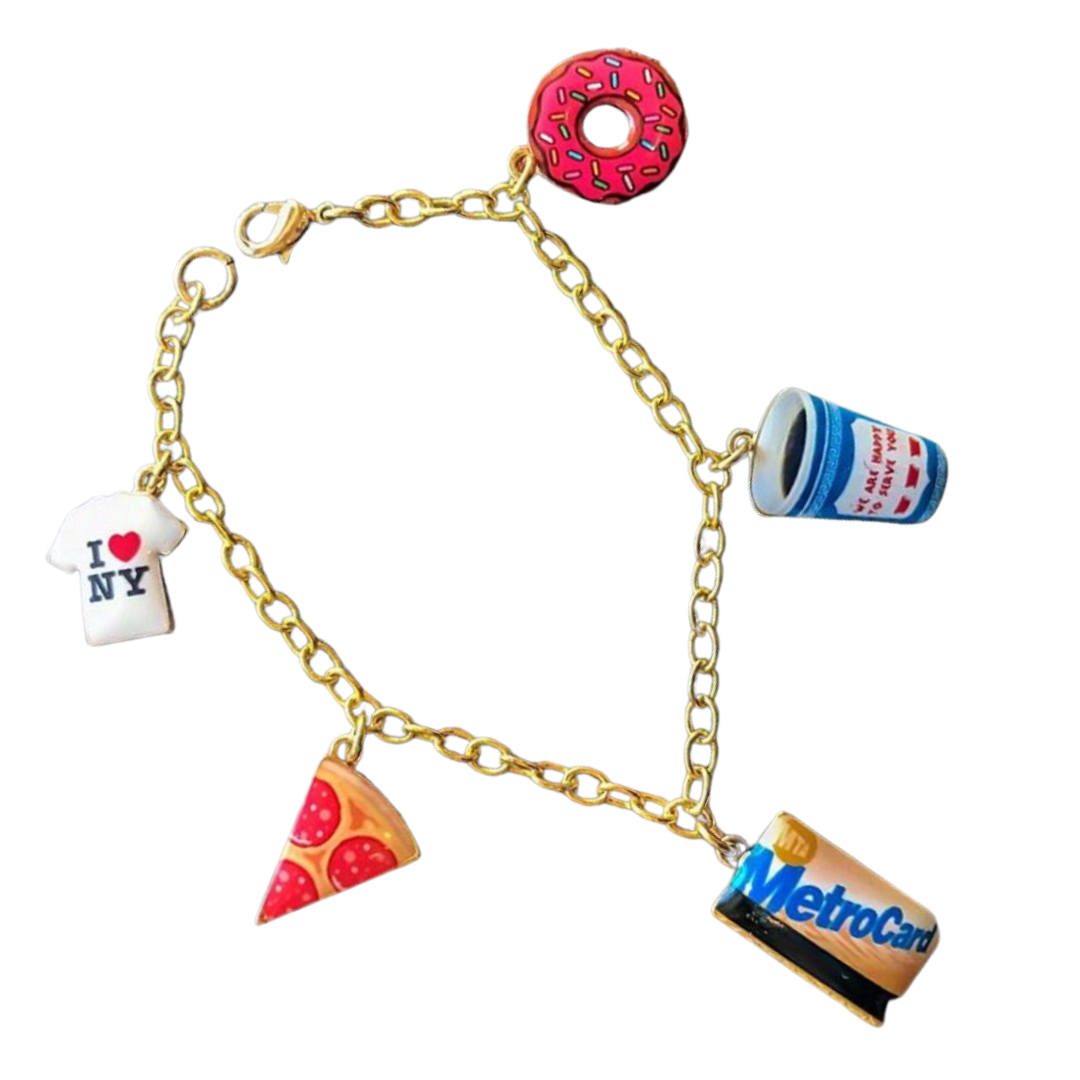 Gold chain bracelet with charms including a pink frosted donut, a high school or college coffee cup, a pizza slice, a MetroCard, a white t-shirt with red and blue text, and an 'I ❤️ NY' symbol.