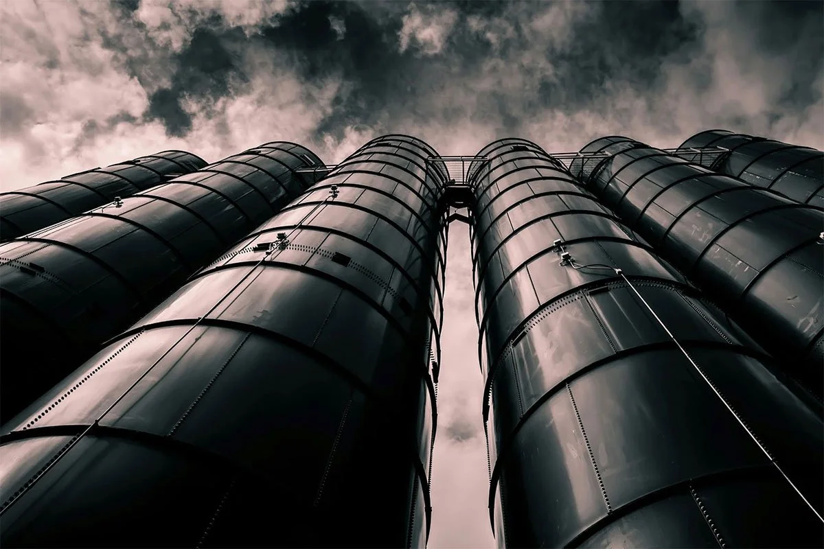 angle view of industrial silos against a cloudy sky, emphasizing tall, cylindrical vessels