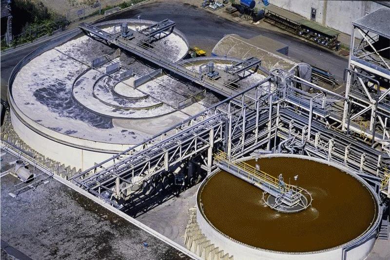 Aerial view of a water treatment facility with large circular tanks and metal walkways.