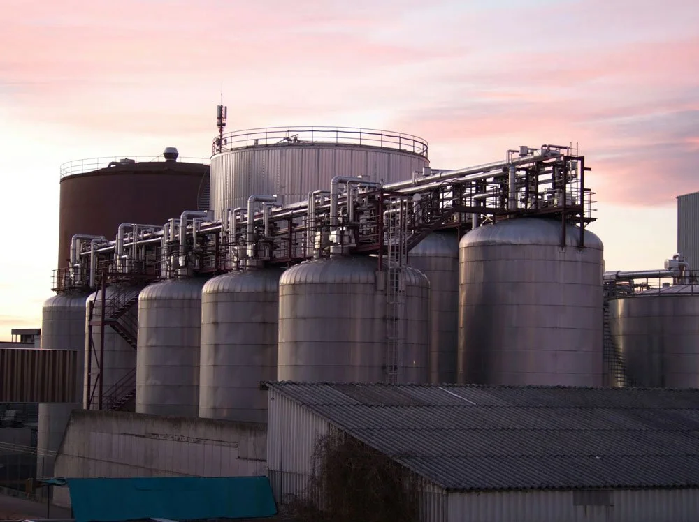 Industrial storage tanks and pipelines at sunset