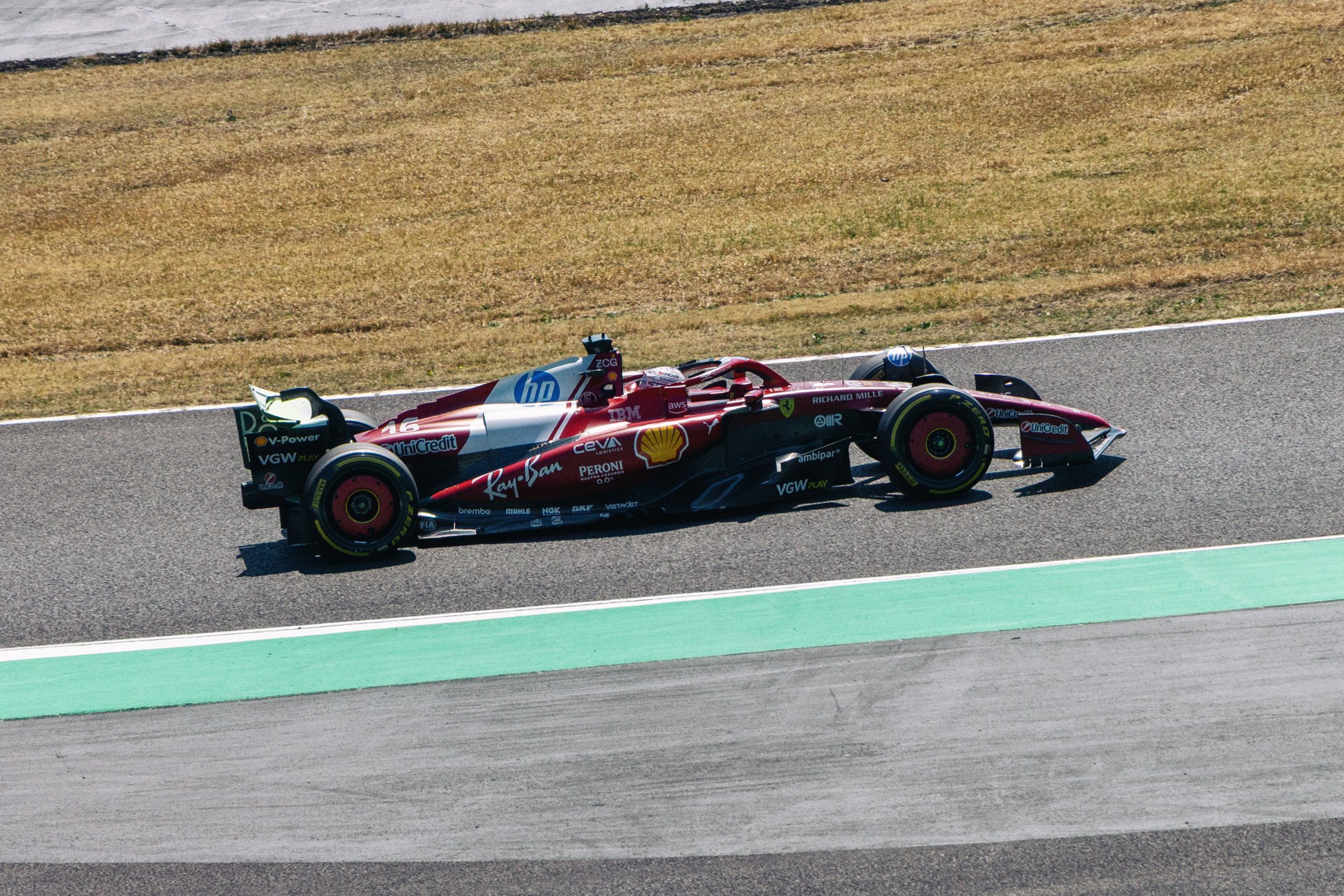 A Formula 1 race car on a racetrack during daytime, with a red and white livery and various sponsor logos.