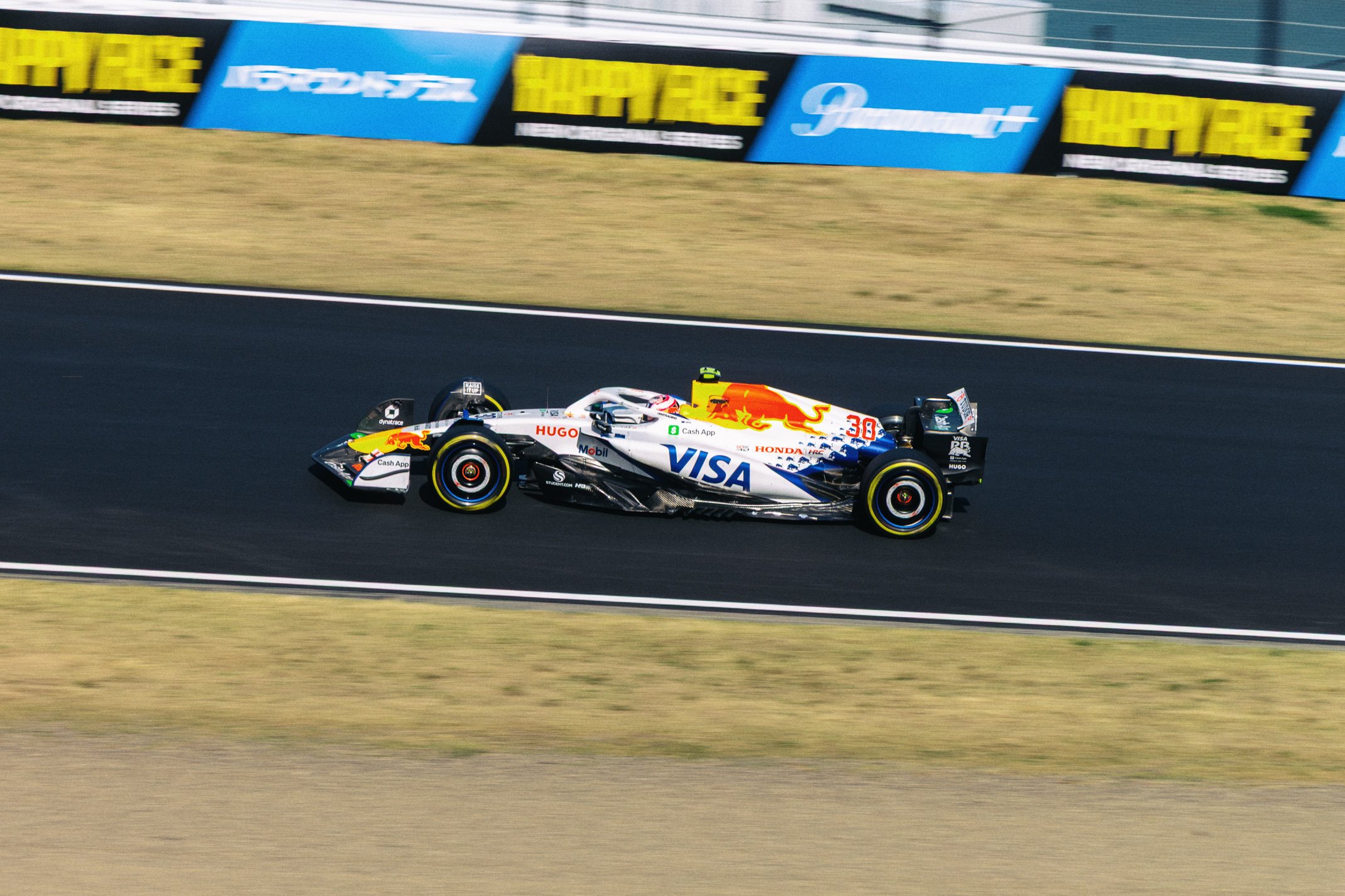 A Formula 1 race car on a race track with advertisement banners in the background.