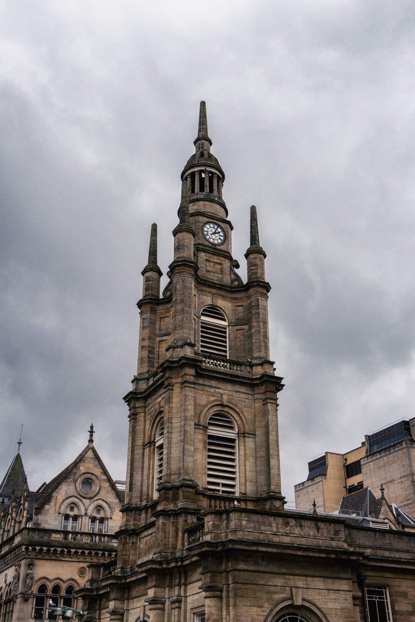 A tall, historic church steeple with a clock, set against a cloudy sky.