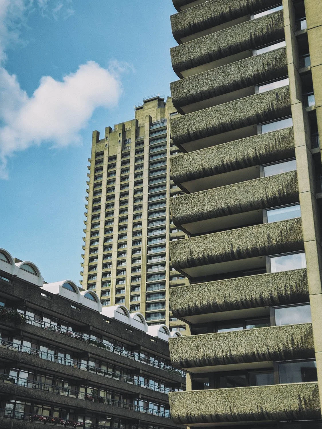 A residential tower at the Barbican Estate in the City of London, photographed from ground level against a blue sky