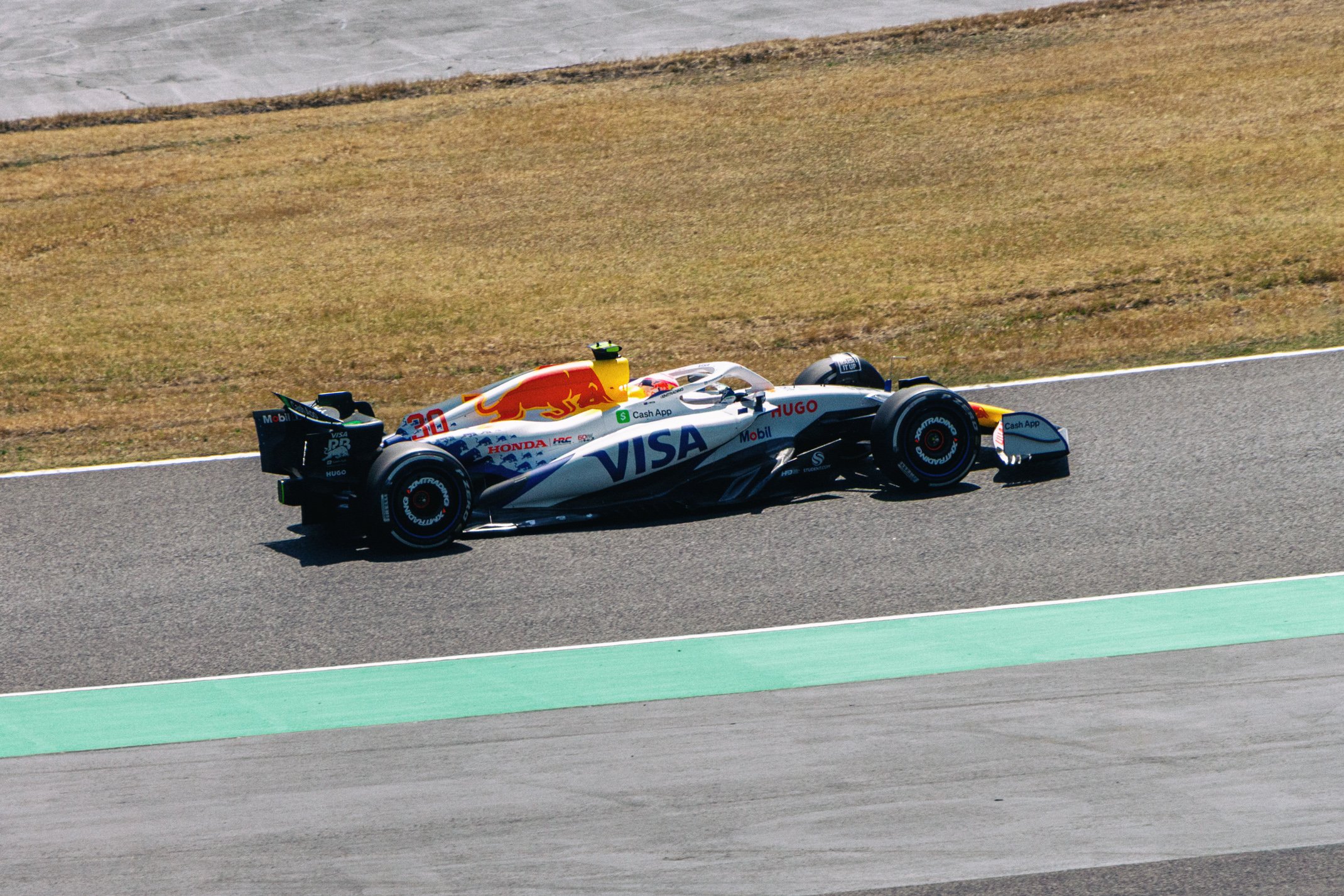 A race car on a track, featuring branding from VISA, Honda, and Red Bull, with a sleek, aerodynamic design in white, blue, and black.