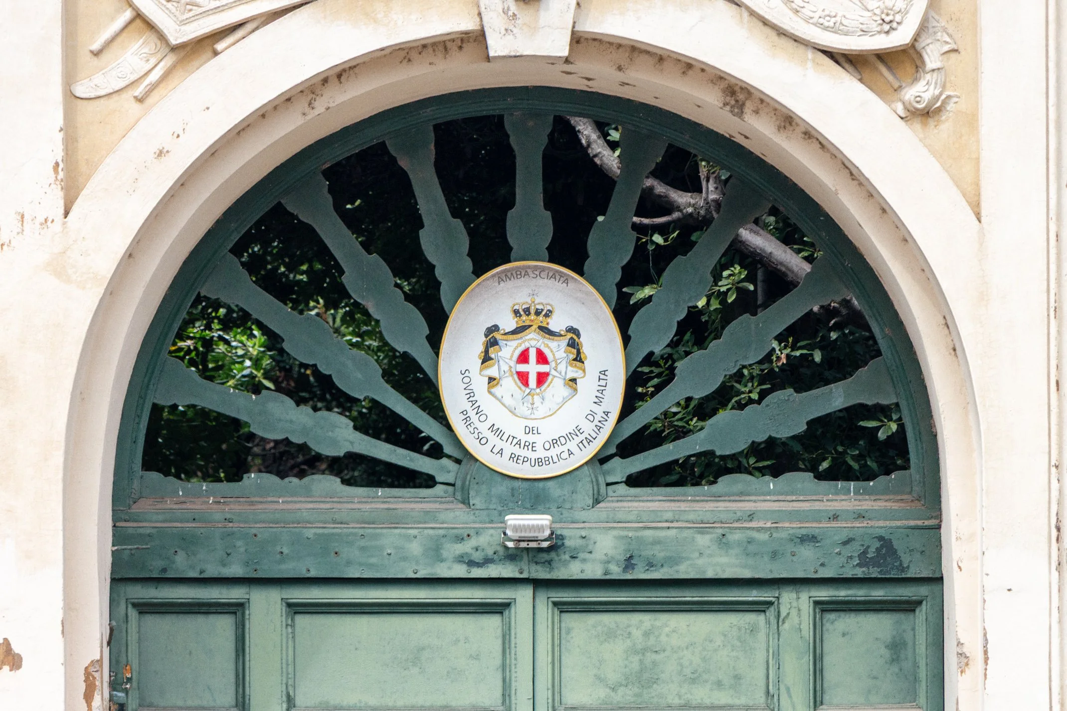 The coat of arms and insignia of the Sovereign Military Order of Malta carved above the green door of their Magistral Villa on the Aventine Hill, Rome