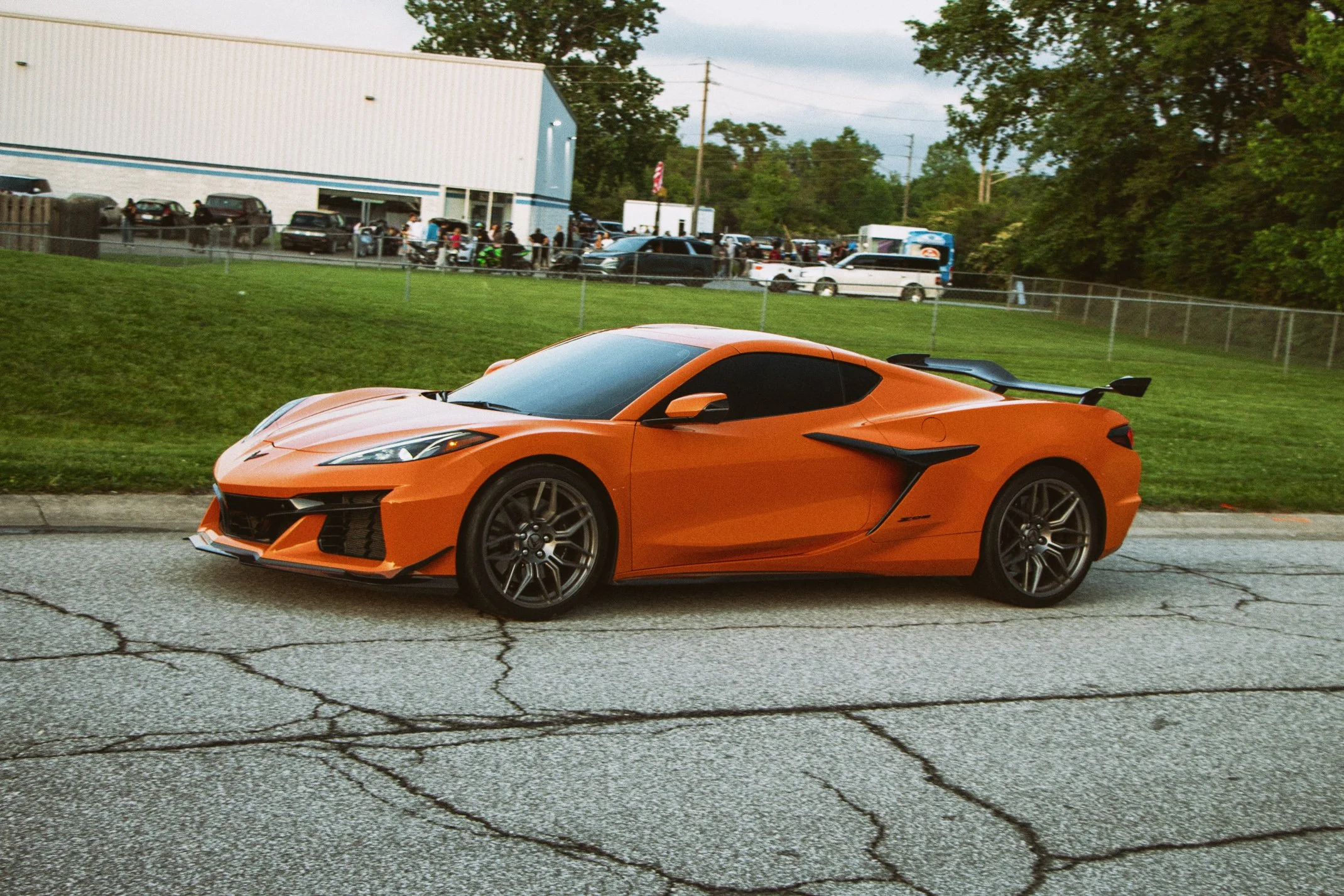 An orange sports car, a Lamborghini, parked on a street with a cracked pavement.