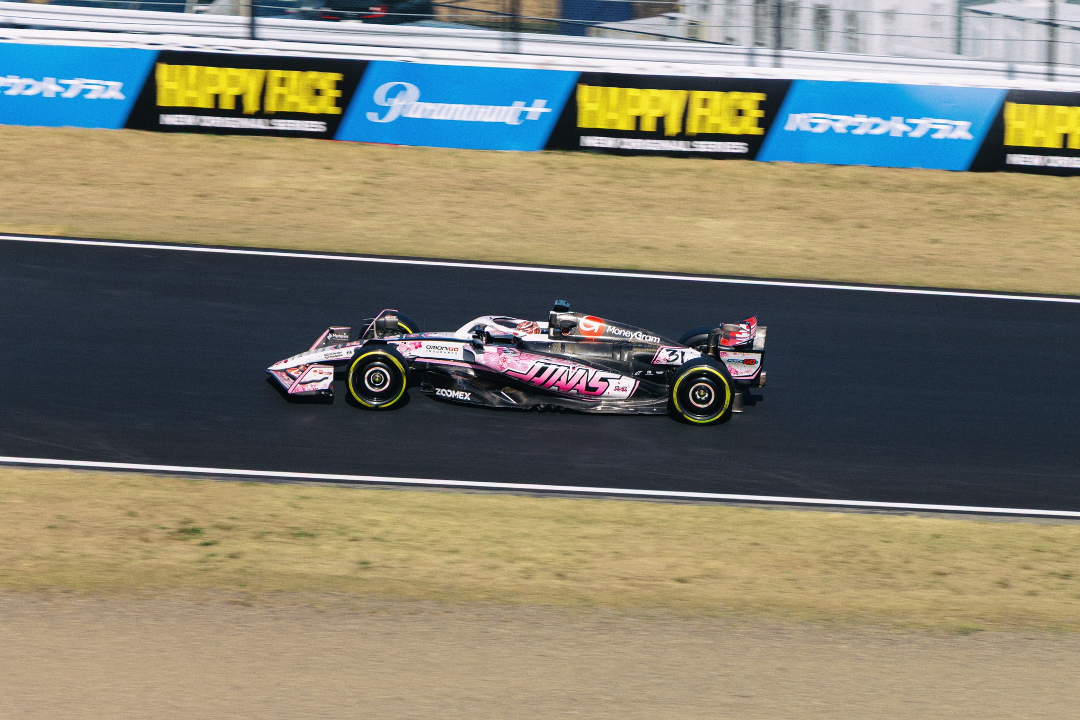 A race car speeding on a racetrack with advertisements on the side panels.