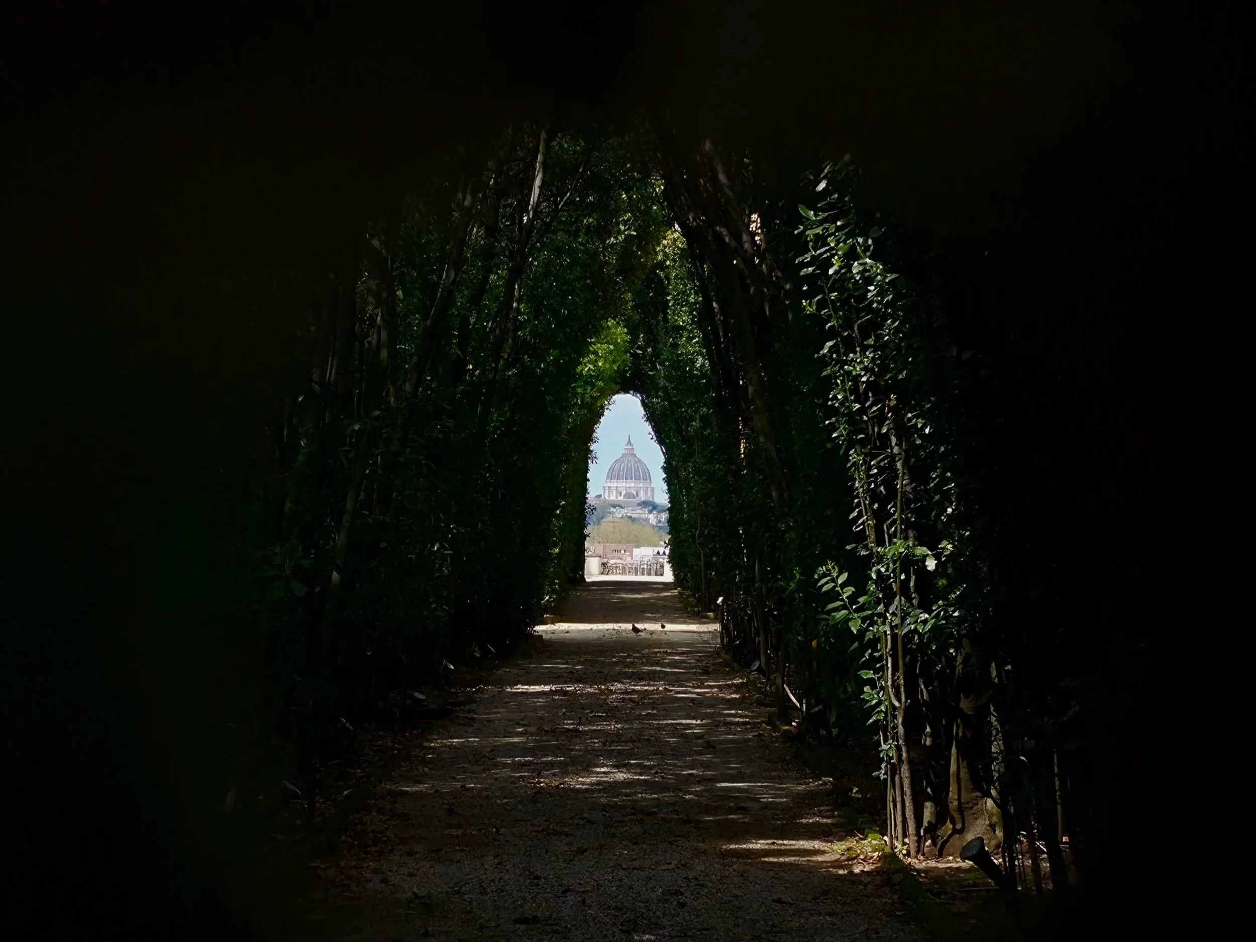 The view through the famous brass keyhole at the Sovereign Military Order of Malta's Magistral Villa gate on the Aventine Hill, Rome, with St Peter's Basilica perfectly framed at the end of a hedge-lined avenue
