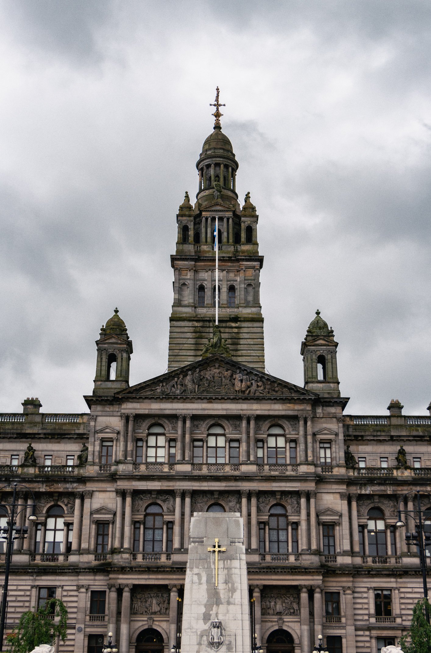 A large historic government building with intricate architectural details, topped with a tall clock tower and a golden cross.