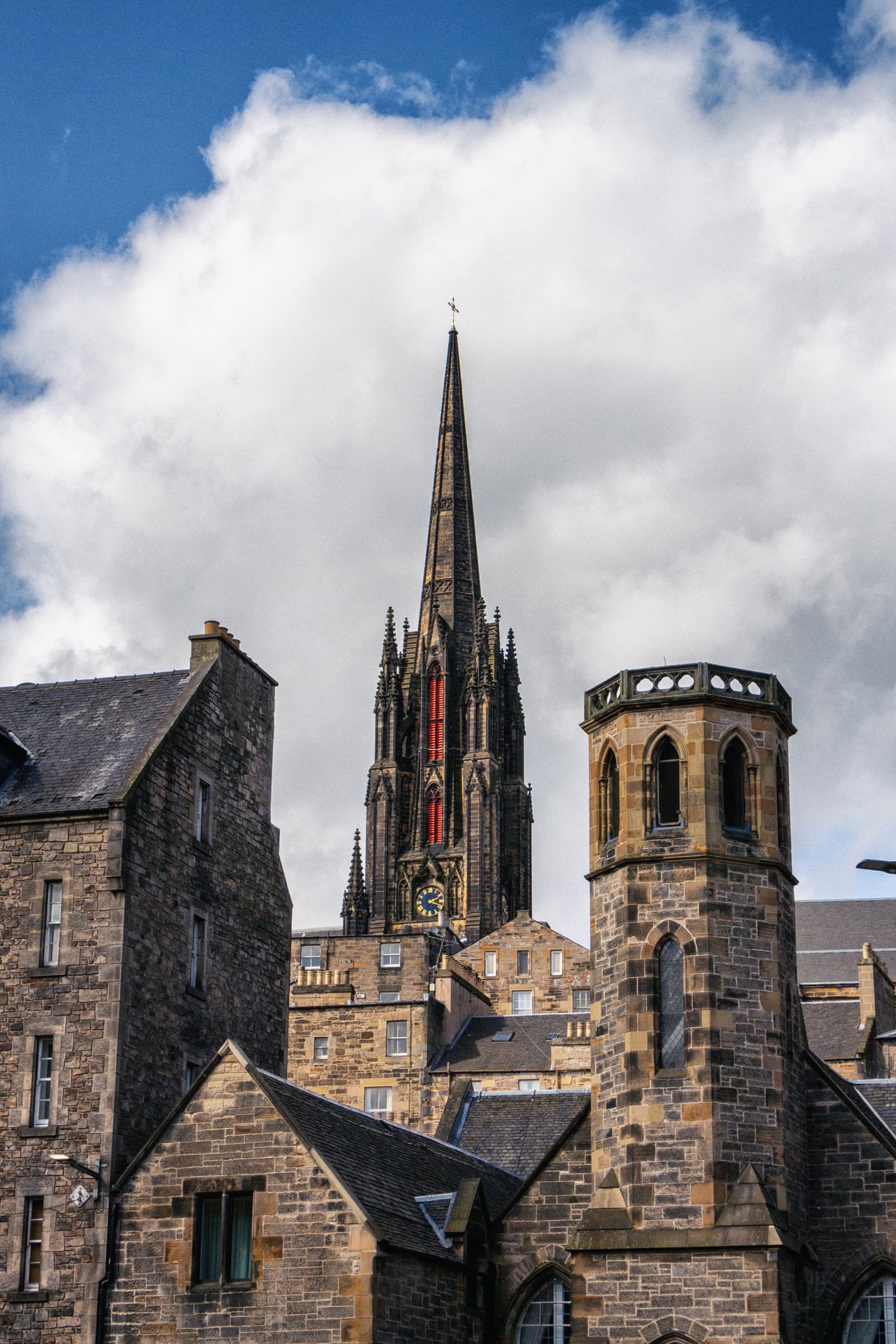 A historic stone church with a tall dark spire and Gothic architecture, set against a cloudy sky.