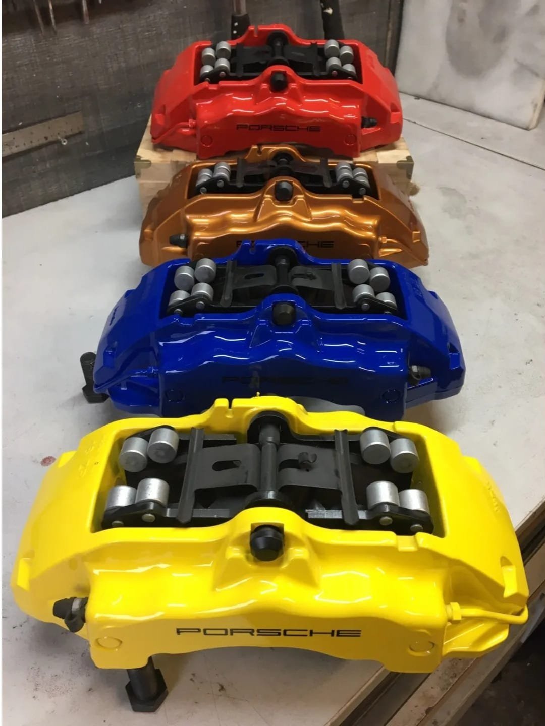 Verschillende autoremklauwen in verschillende kleuren, waaronder geel, blauw, oranje, en rood, met het Porsche-logo erop.