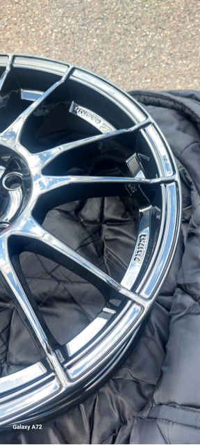 Een close-up van een glanzende metallic velg op een donkere ondergrond.
