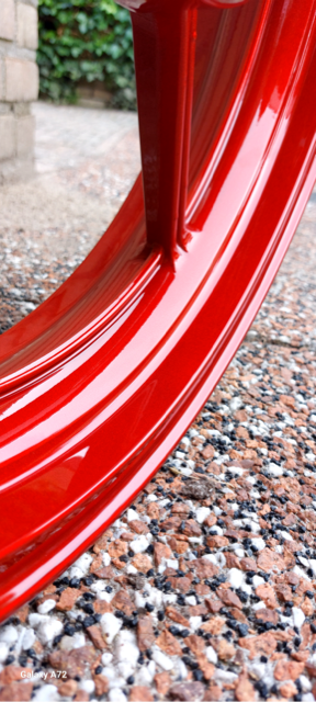 Rood geverfde autovelg op grindondergrond.