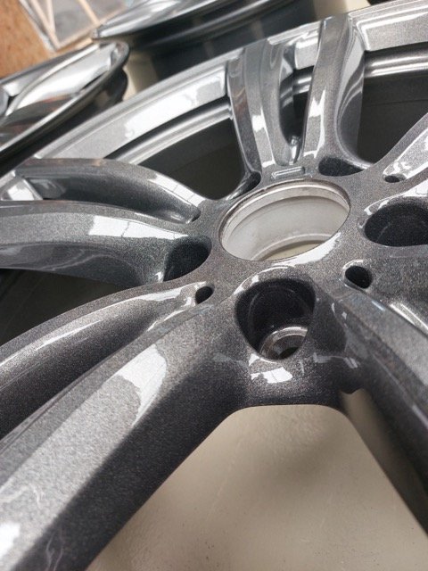 Close-up van een glimmende, metalen velg met meerdere spaken.