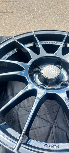 Close-up van een zwarte velg met meerdere spaken, liggend op een donkere stof.