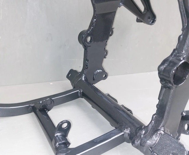 Zwarte motorfietsframe tegen een grijze achtergrond, zijaanzicht.