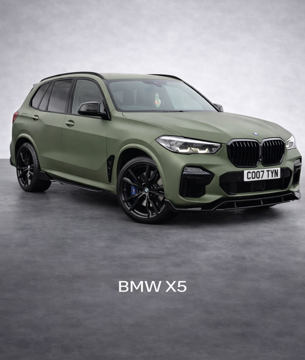 Green BMW X5 SUV with black wheels, parked indoors on a gray surface, with "BMW X5" text at the bottom.