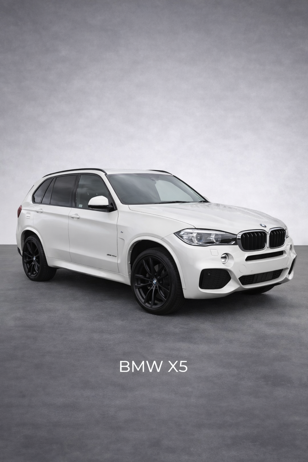 A white BMW X5 SUV with black wheels, parked on a grey floor against a plain grey background.