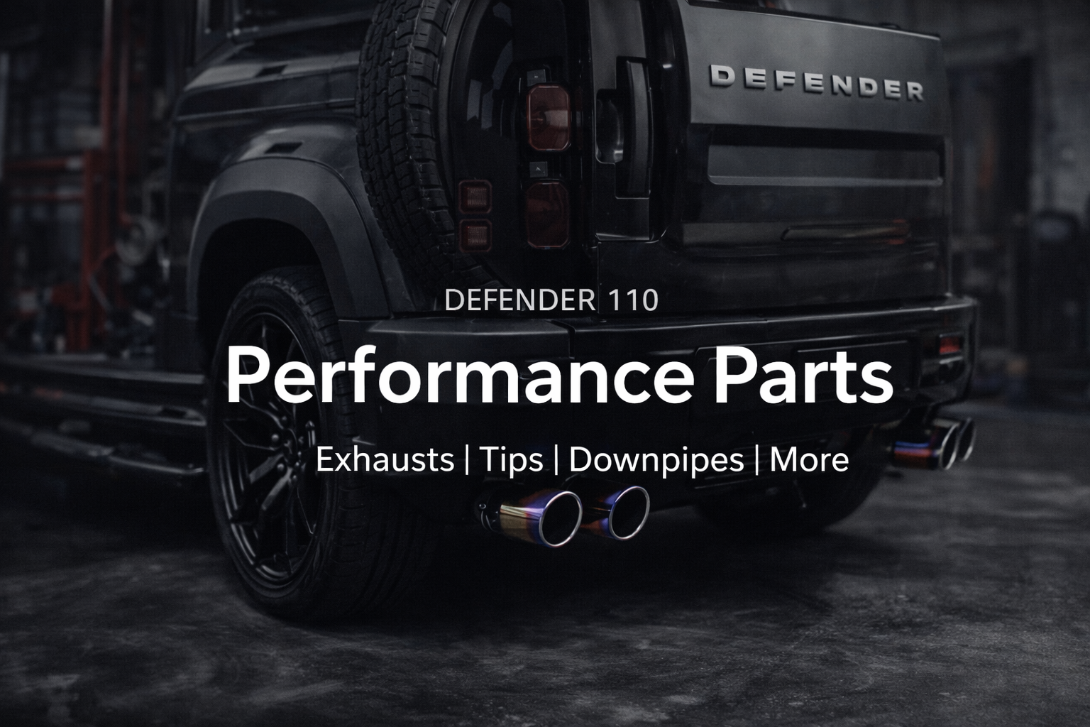 Rear view of a black Land Rover Defender 110 with performance car exhaust tips, in a garage setting, with text overlay promoting performance parts like exhausts, tips, downpipes.