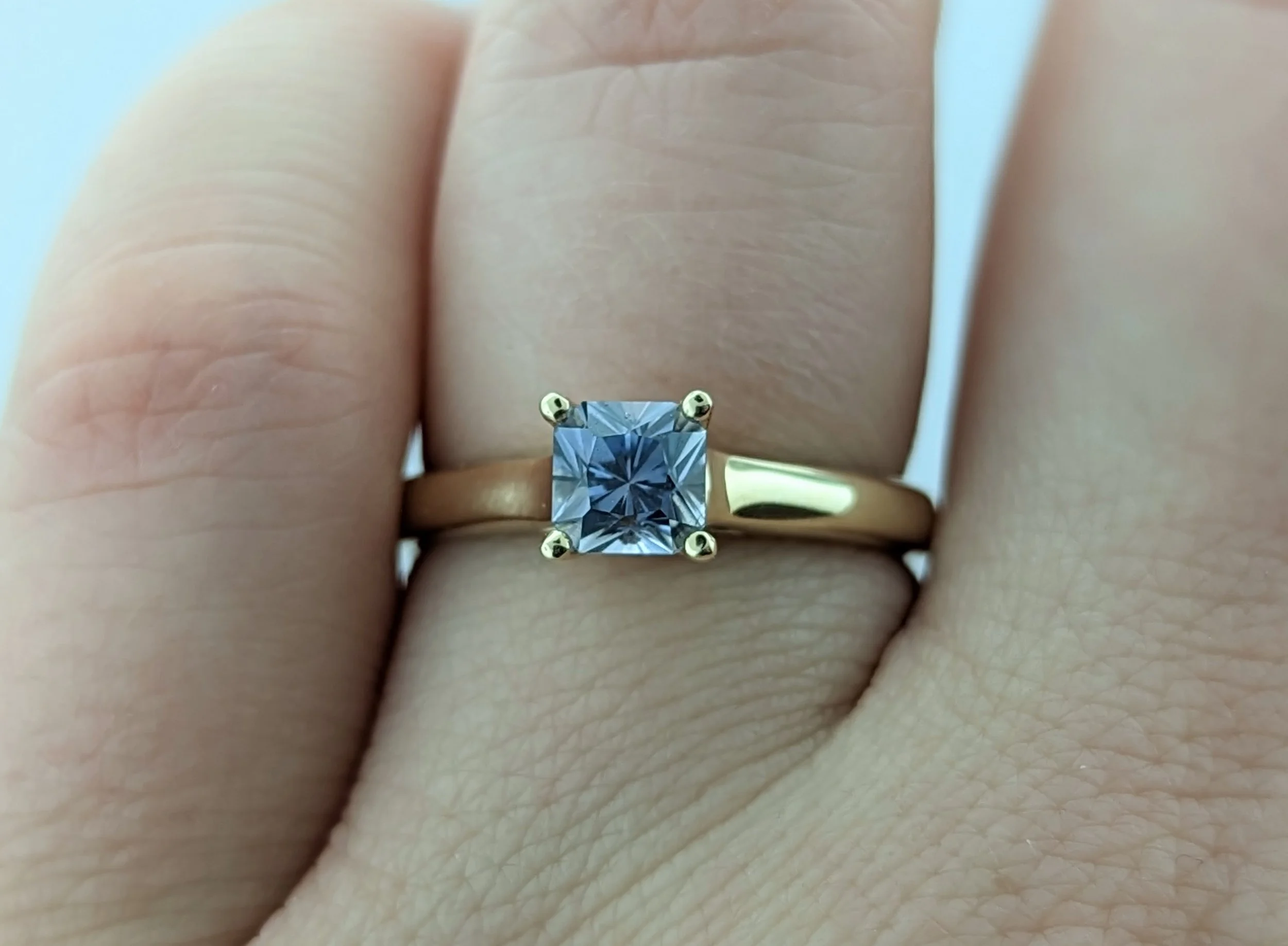0.97ct Asscher-cut light grey/lavender Montana Sapphire ring in 14k yellow gold with hidden side diamonds.