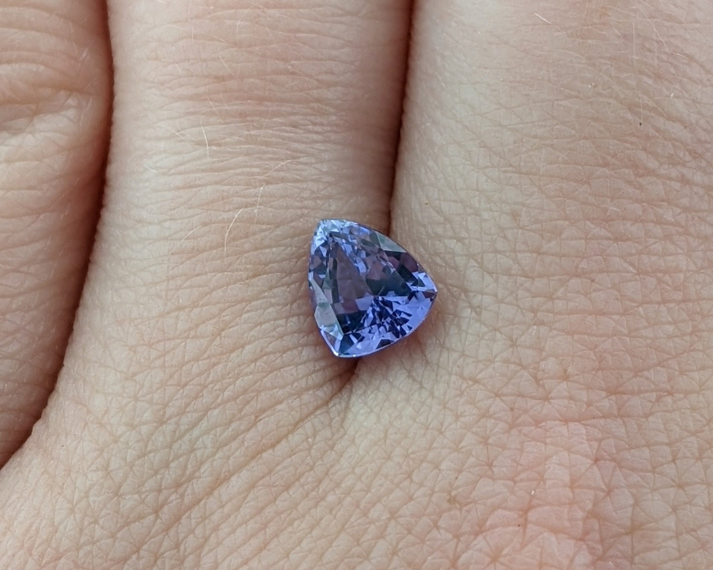 Trillion purple sapphire displayed on a hand