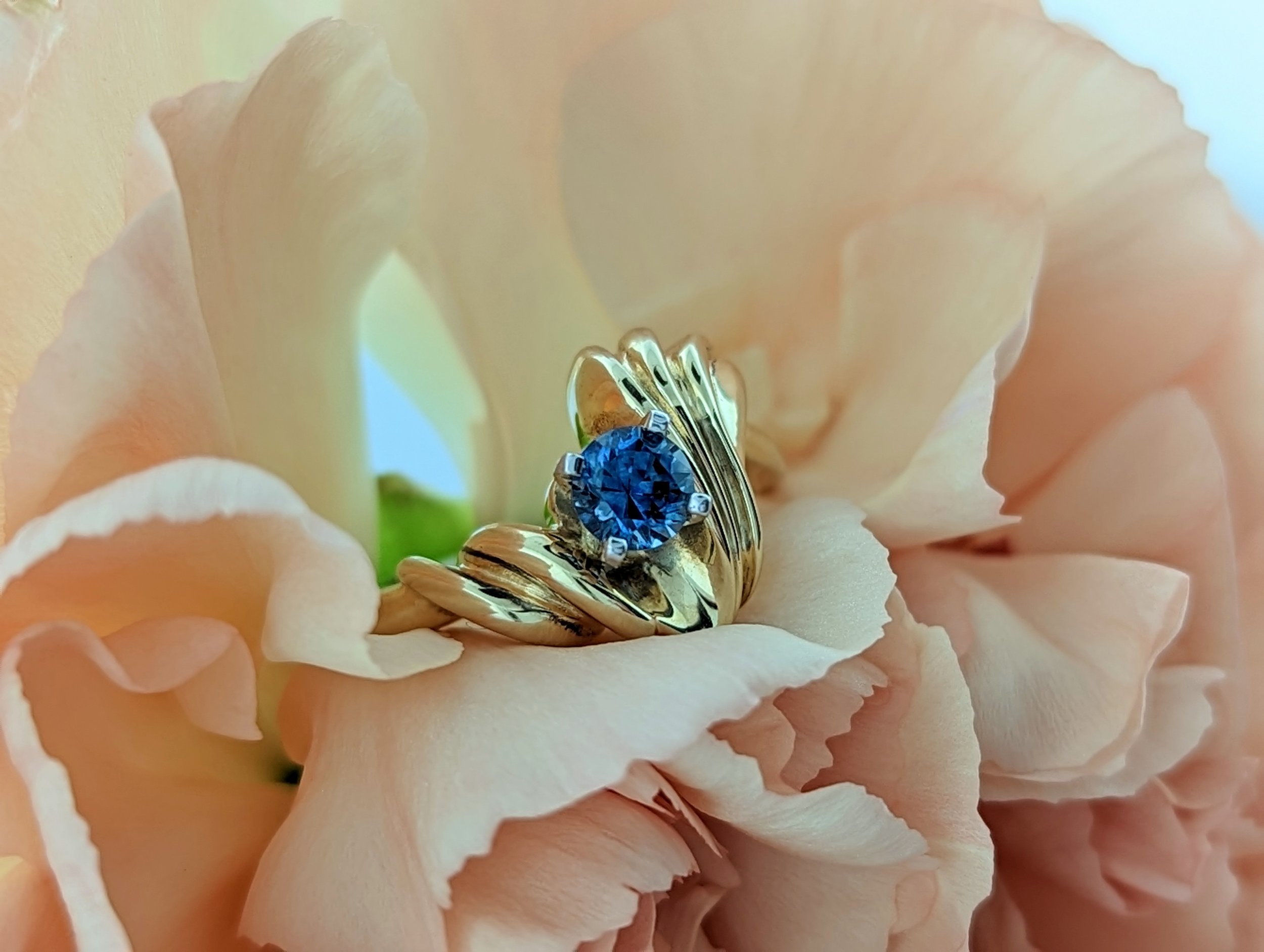 1.02ct round cut Montana Sapphire ring set in a unique 14k yellow gold freeform design, showcasing elegant curves and a rich blue gemstone.