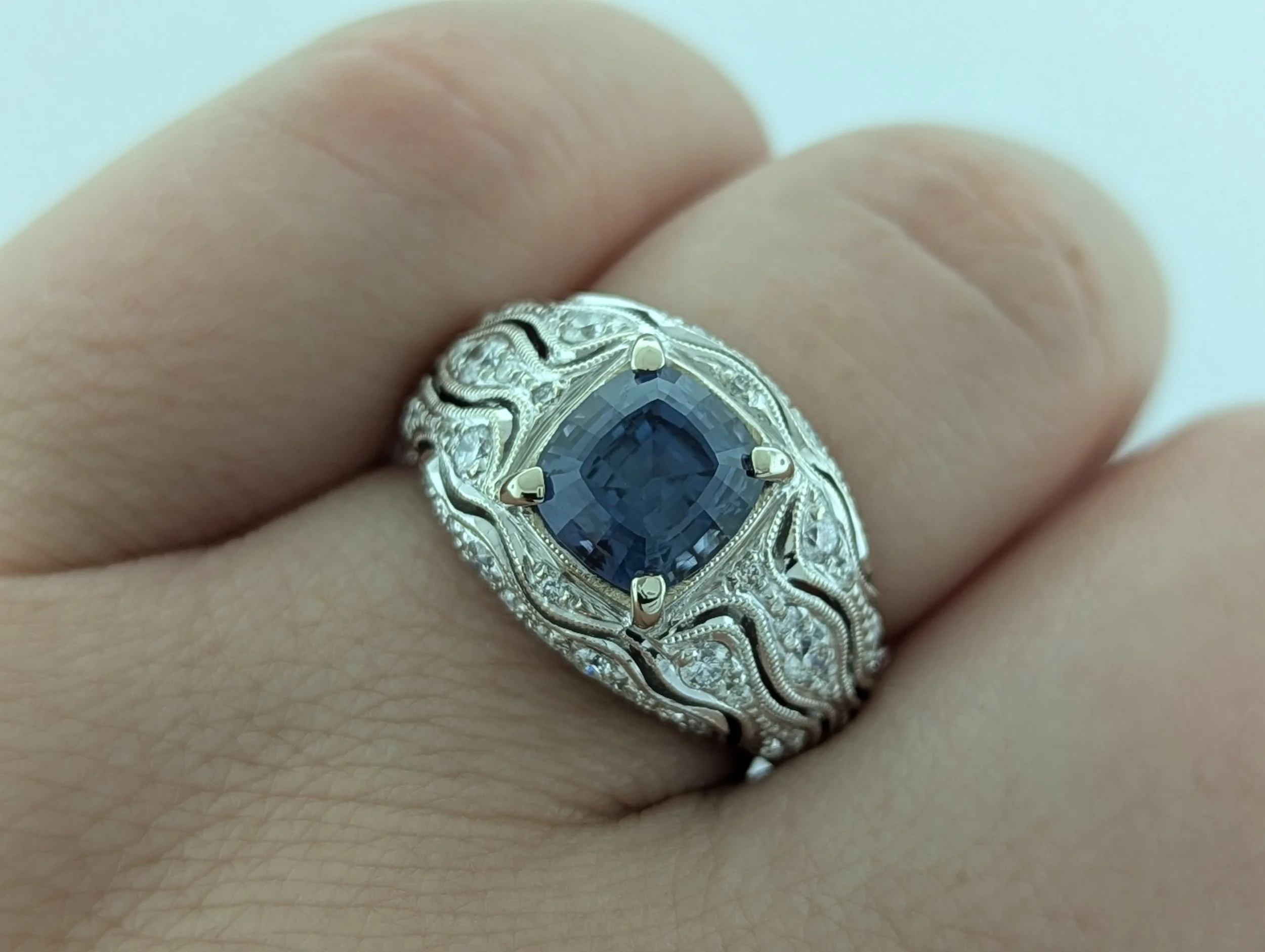 2.8ct cushion cut blue Montana Sapphire ring with diamond accents and intricate art deco design in 14k white gold.