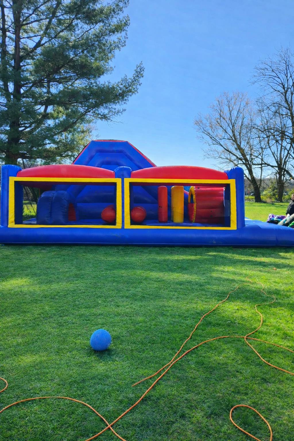 Inflatable playground with obstacle course in purple, yellow, and red colors outdoors.