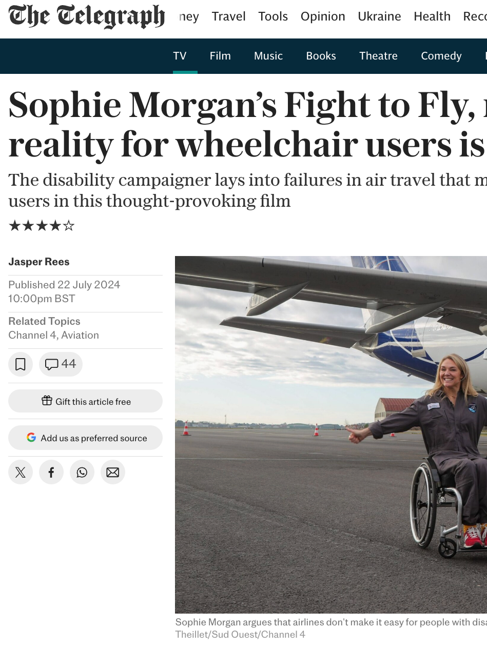 A woman in a wheelchair standing in front of a large airplane on an airport tarmac, smiling and holding her arms out.