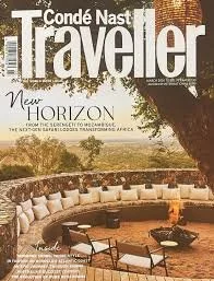 A vibrant landscape of rolling green hills with patches of yellow and orange wildflowers, mountains in the background, and a dirt trail winding through the terrain.