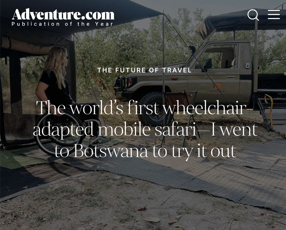 A woman in a wheelchair at a mobile safari camp, with a truck and outdoor camping setup in Botswana.