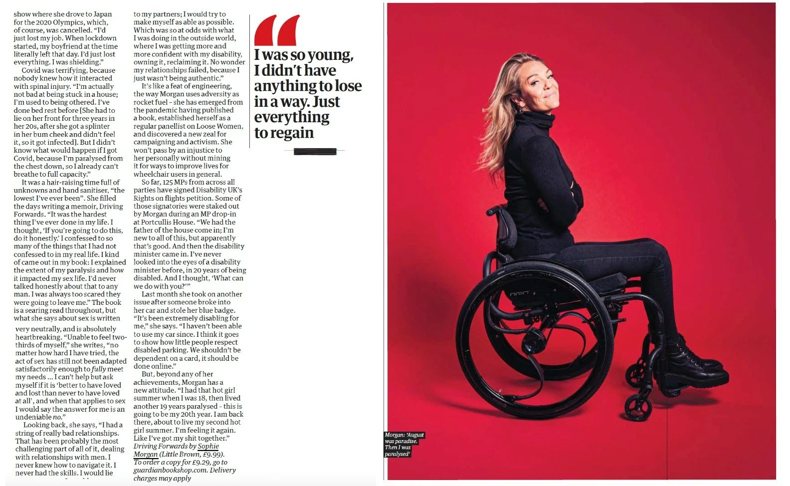 Young woman in modern black wheelchair, wearing black jacket and pants, posing with crossed arms against bright red background, smiling confidently.