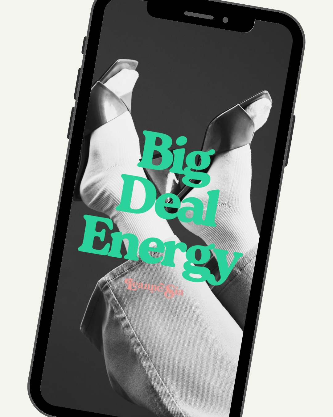 Black mobile phone displaying the cover of a book titled 'Big Deal Energy' by Jeanna Gia. The cover features a black-and-white photo of a person in a white glove holding a smartphone.