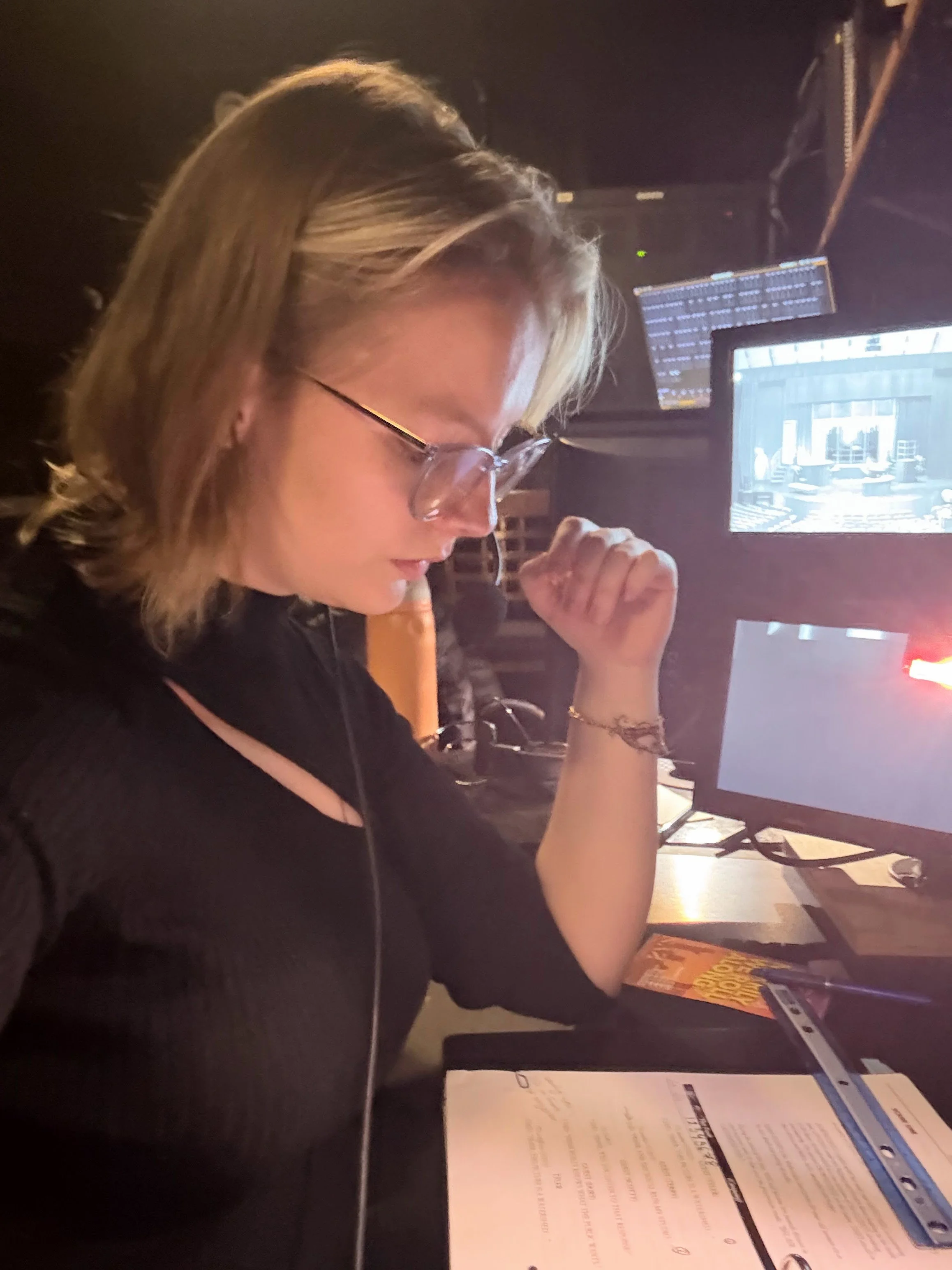 A woman with blonde hair and glasses focused on reading a menu at a restaurant or cafe.