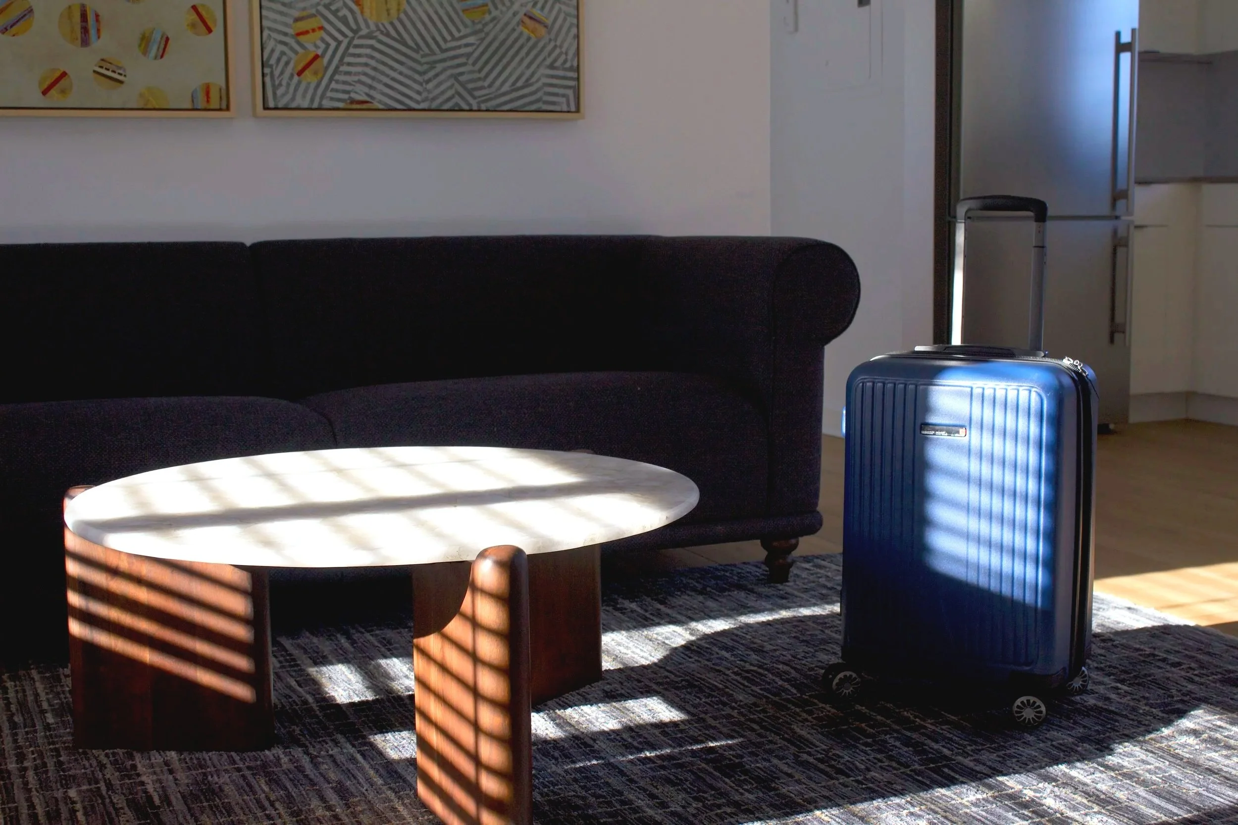 business traveler's suitcase in apartment living room with couch and coffee table