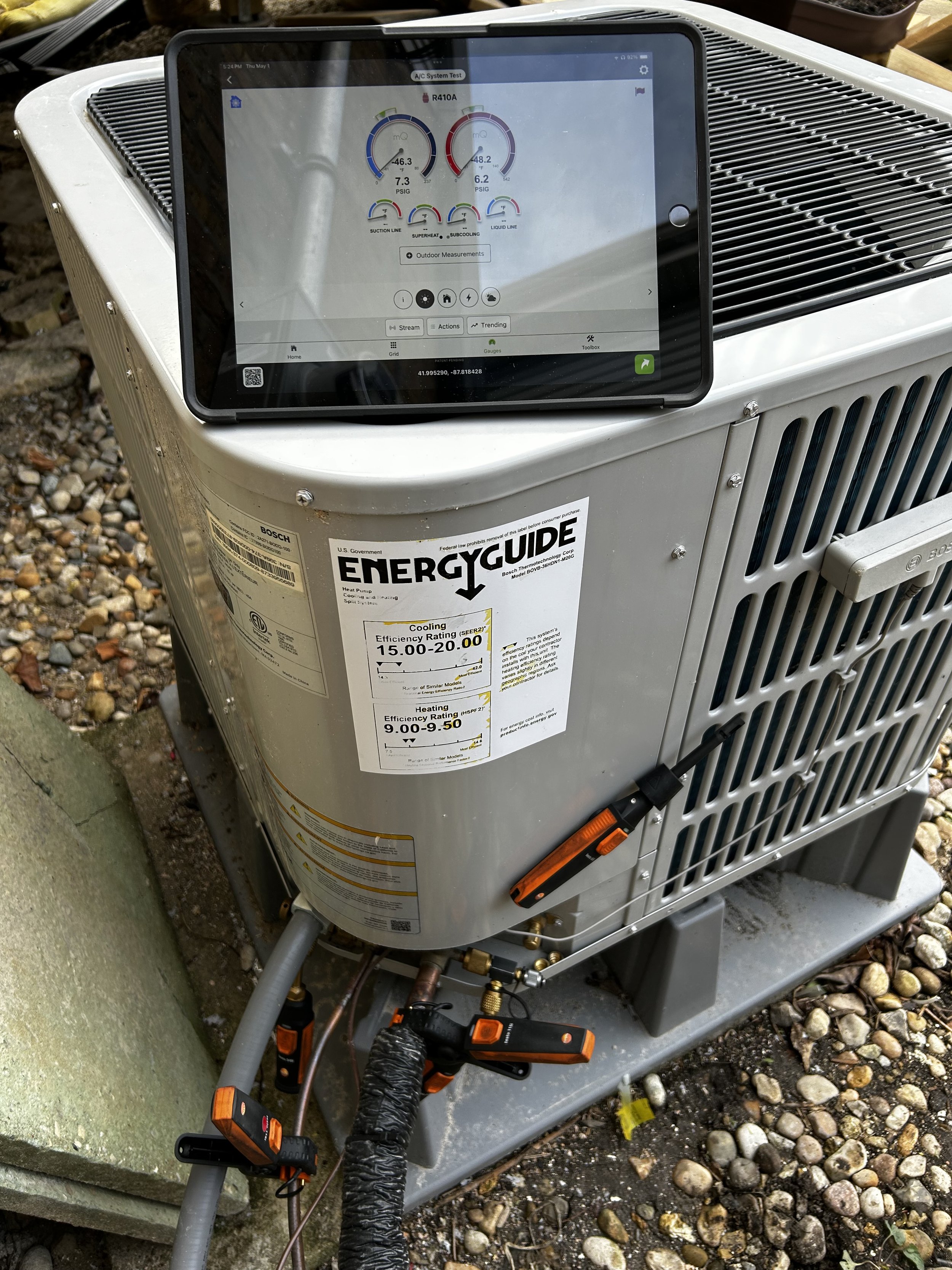 An outdoor HVAC unit. There are various tools and sensors attached to the unit for tune-up