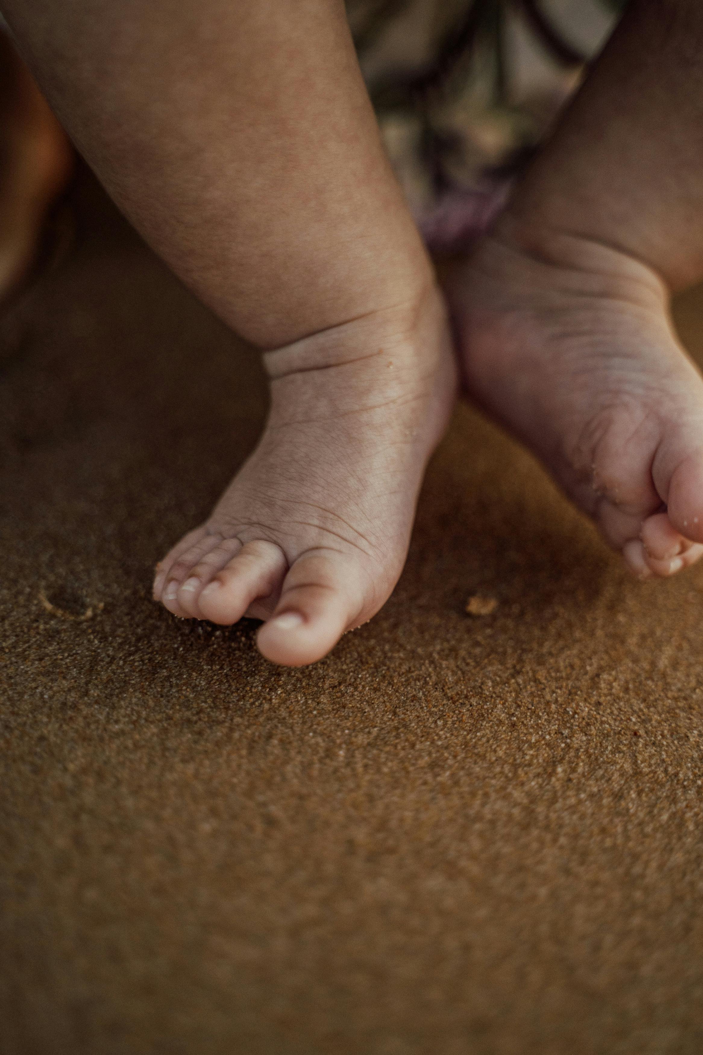 Close-up of a baby's feet touching sand.
