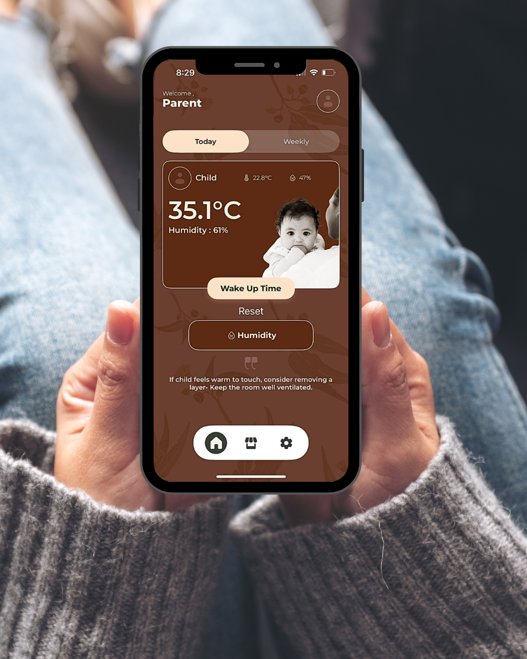 Smartphone screen displaying a child temperature monitoring app showing a child's temperature at 35.1°C, humidity at 61%, with a photo of a baby, and options for wake-up time and humidity adjustment.