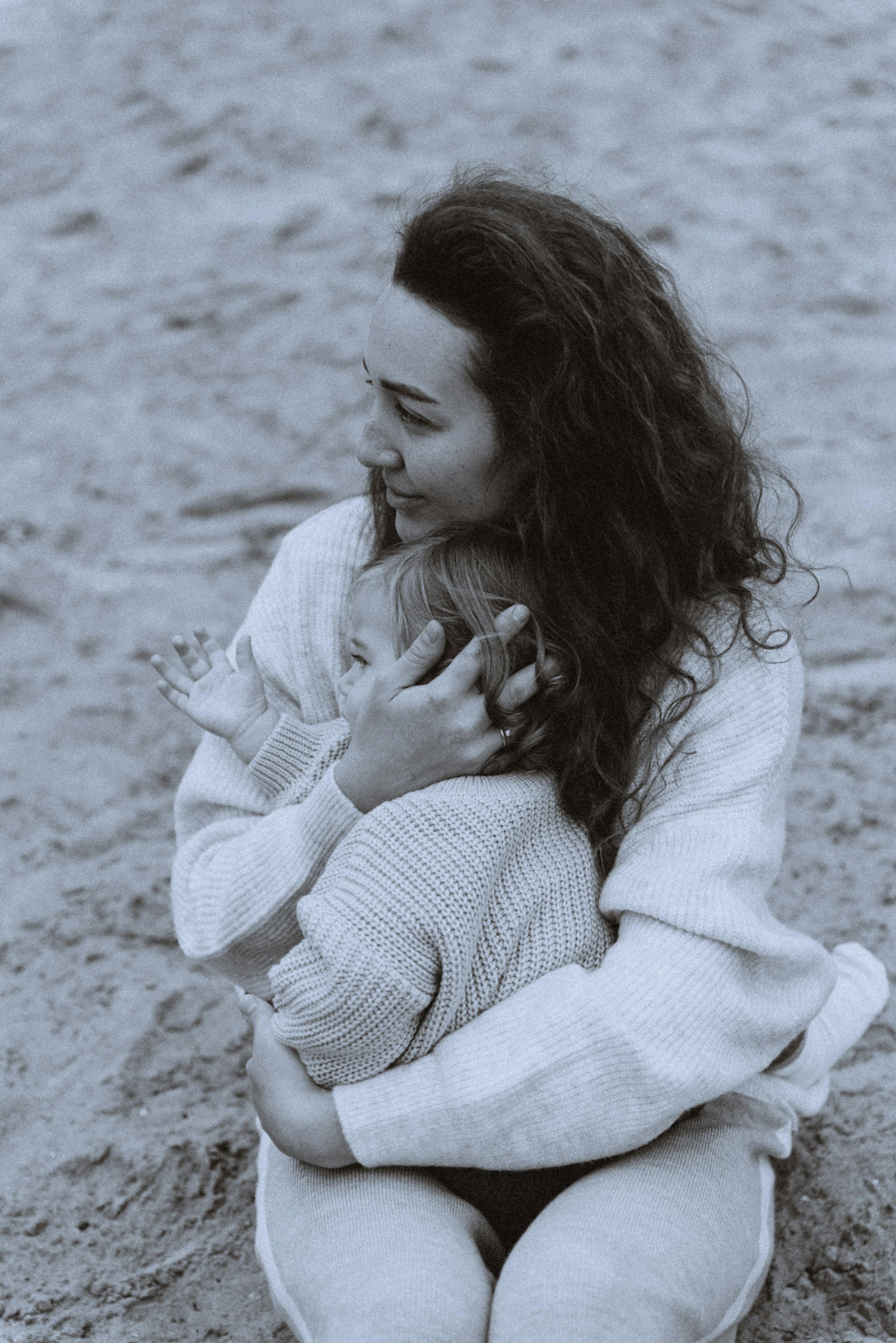 Woman holding child on beach with knitted sweaters