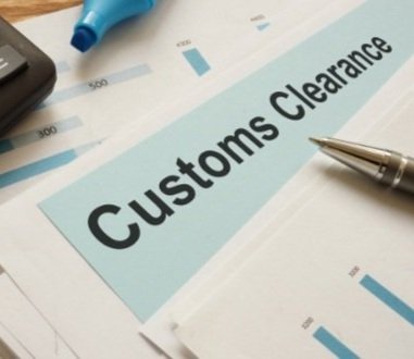 A document labeled "Customs Clearance" on a desk with a pen, highlighter, and calculator.
