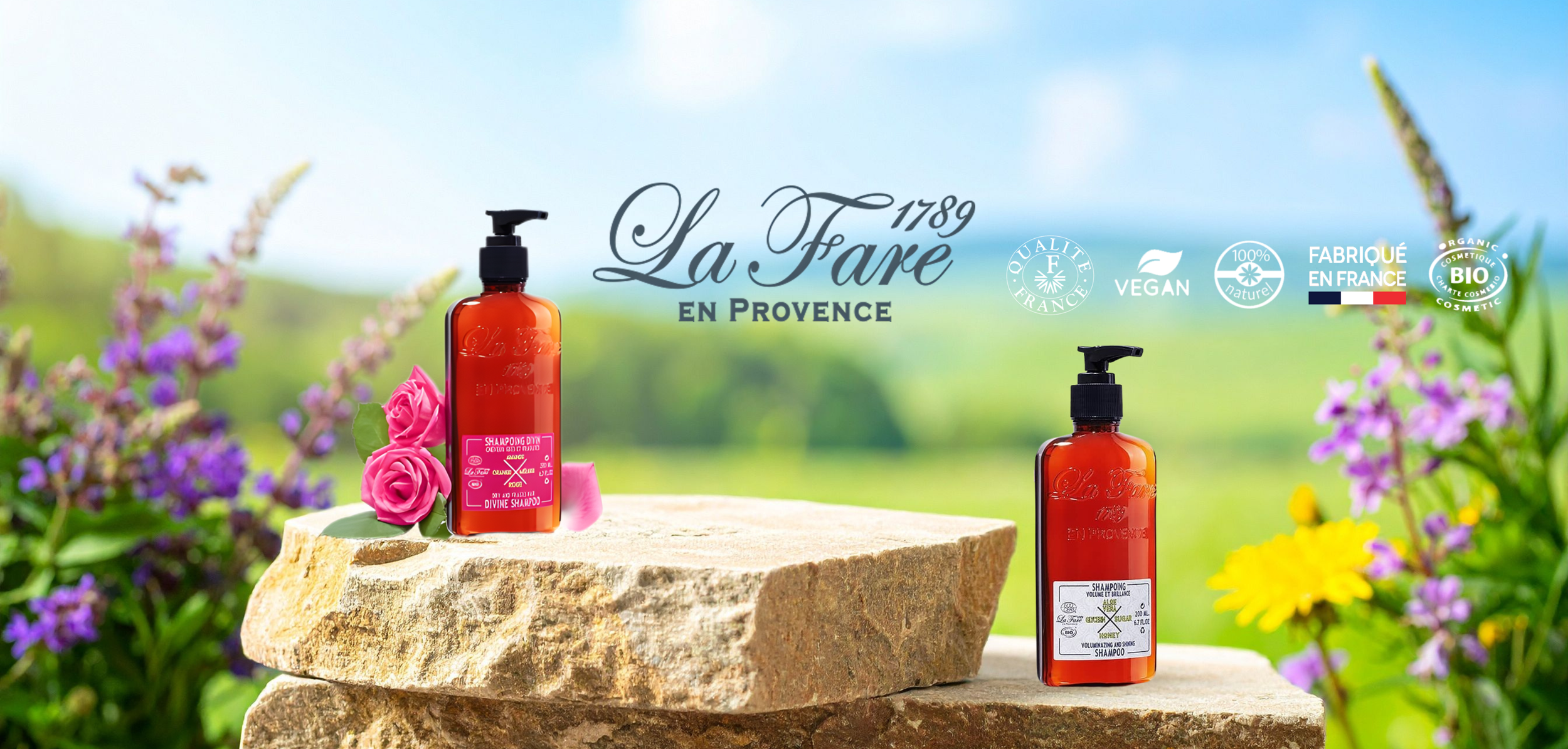 Deux bouteilles de shampooing dans un décor naturel avec des fleurs et un ciel bleu, marque La Fare, Provence, sur une roche.