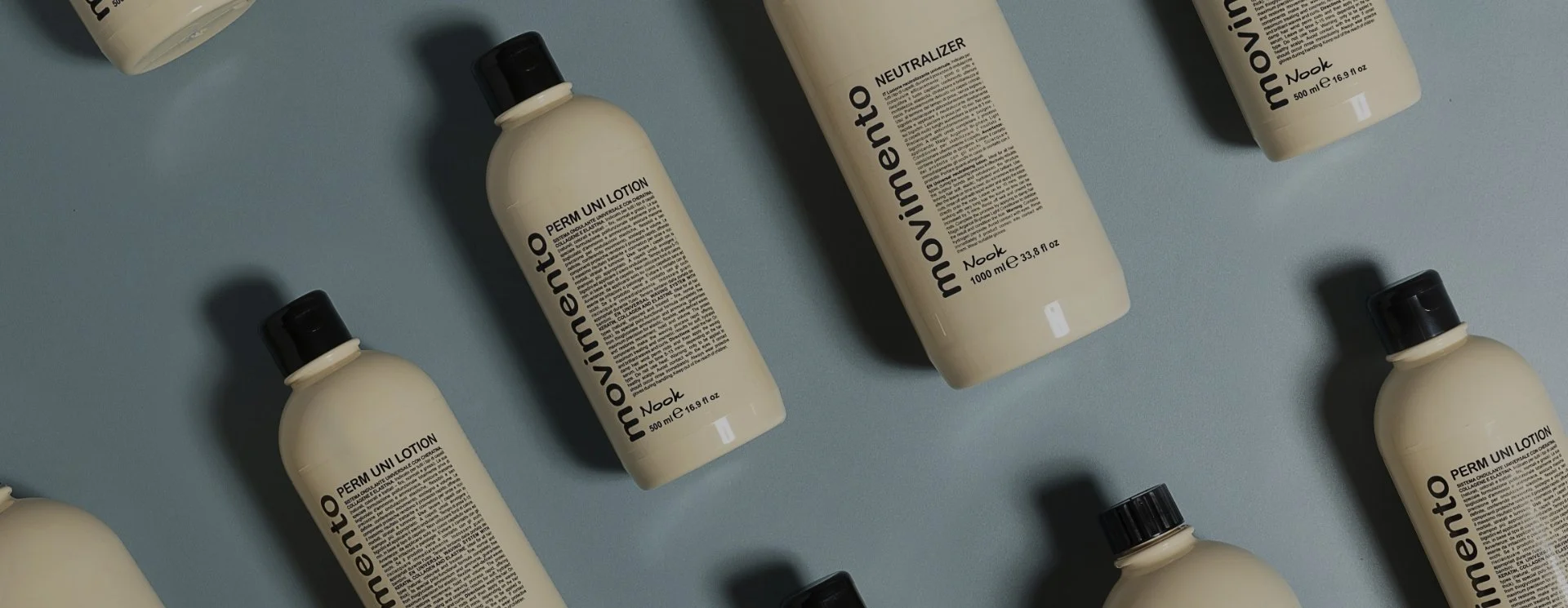 Bouteilles de lotion blanche avec capuchon noir disposées sur une surface bleue.